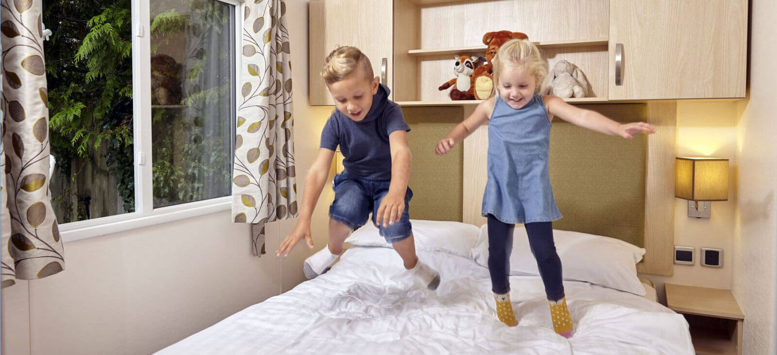 two kids jumping on caravan bed