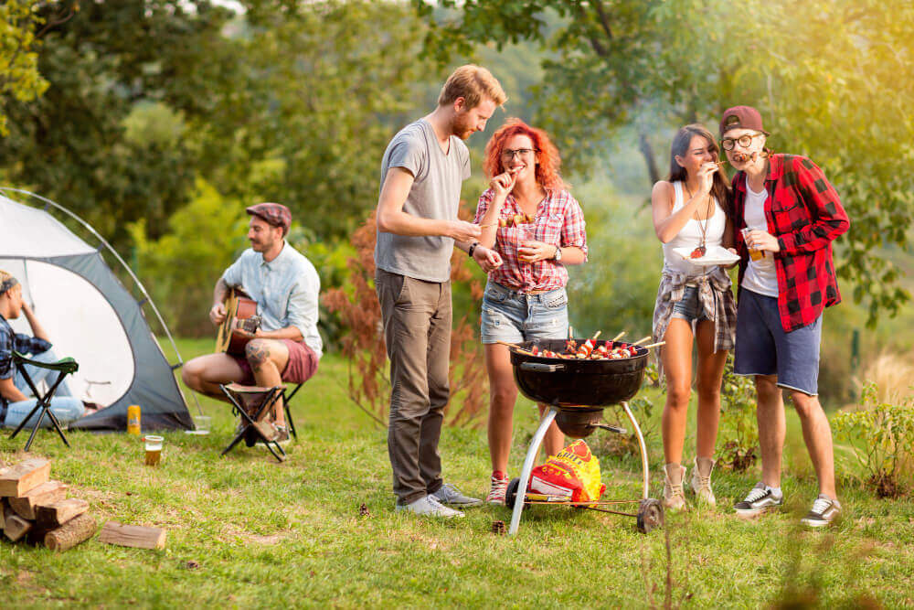 Holiday park BBQ safety - group enjoying safe BBQ near tent.