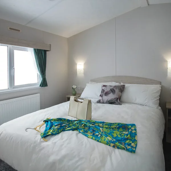 A stylish dress and handbag on the double bed of the Delta Saffron Deluxe caravan