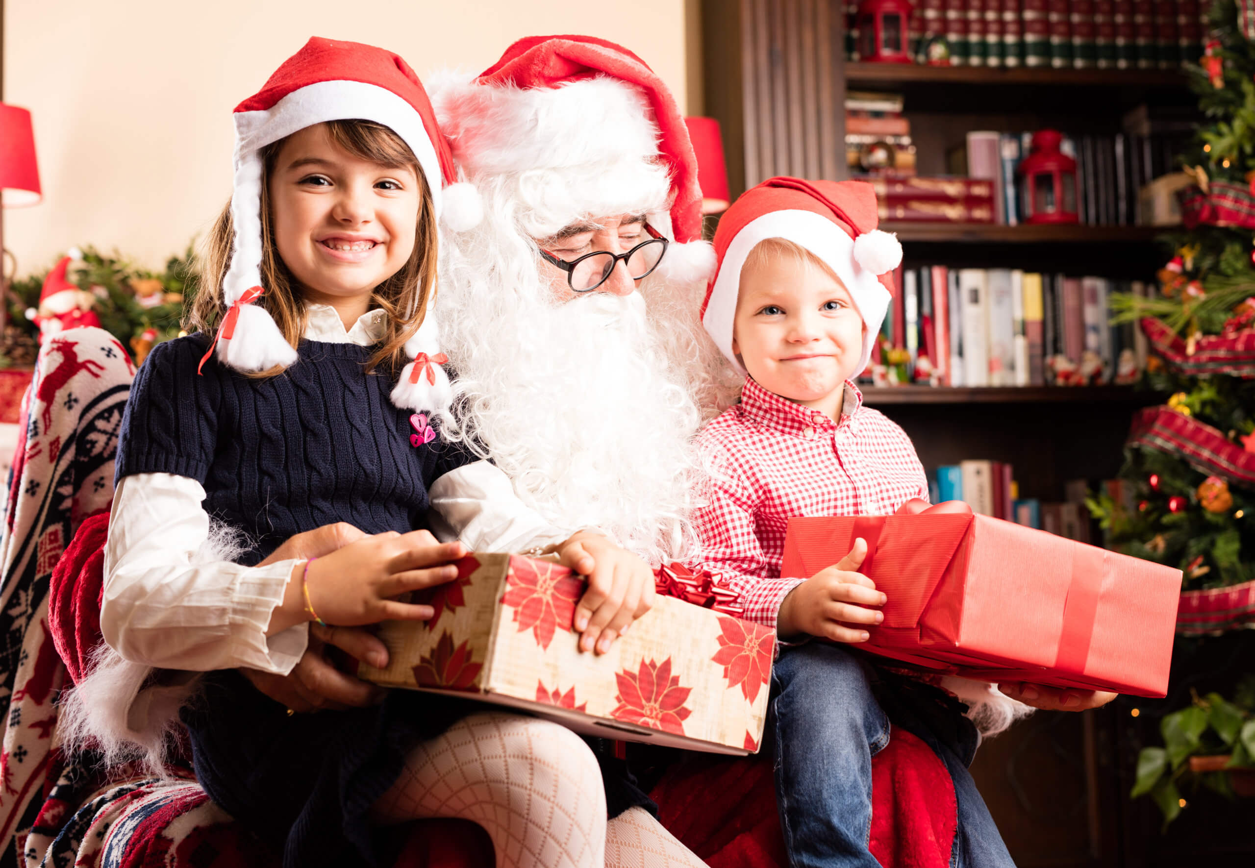 Smiling kids with presents sat on Santa's lap