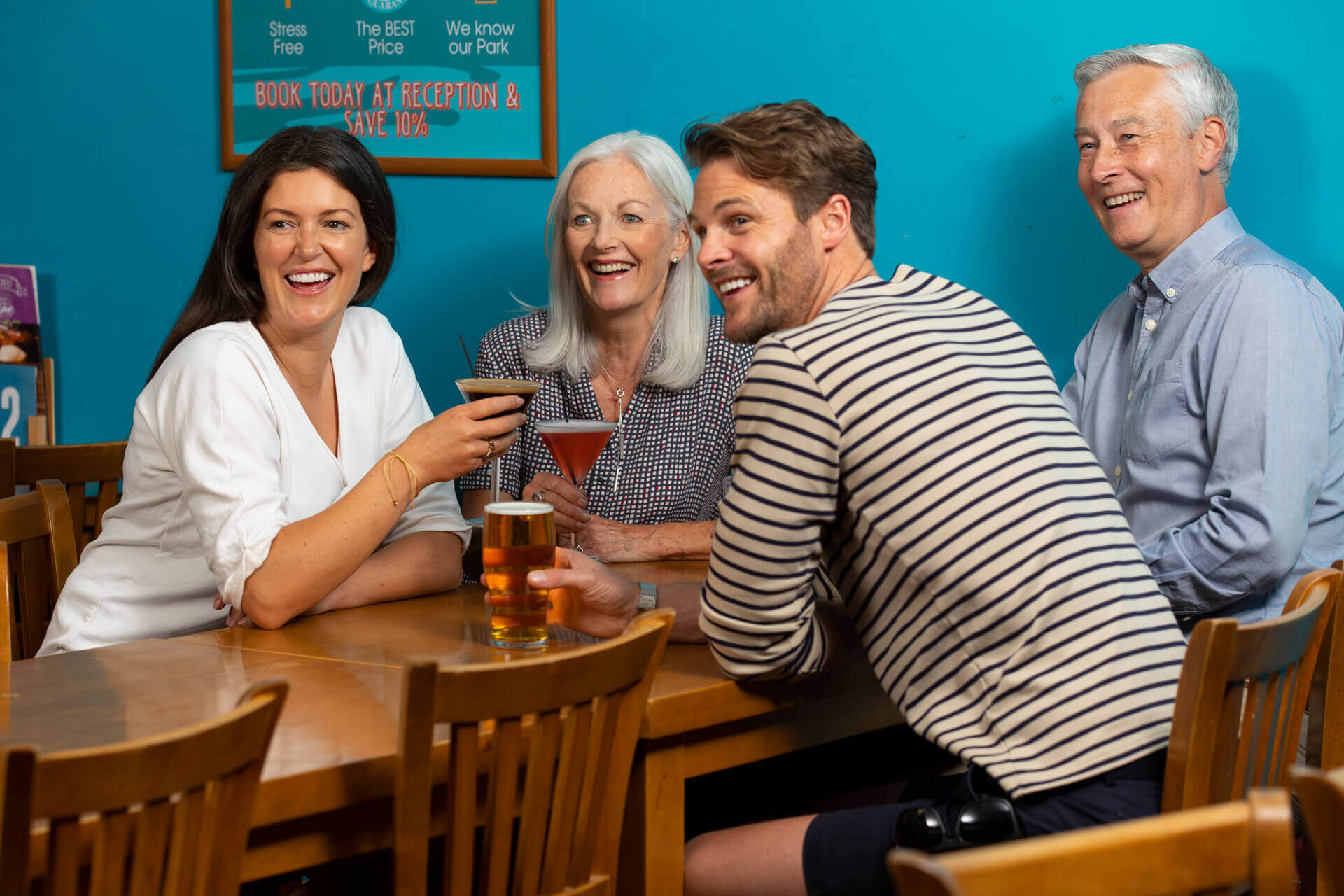 Group of adults sat at a tables laughing and drinking