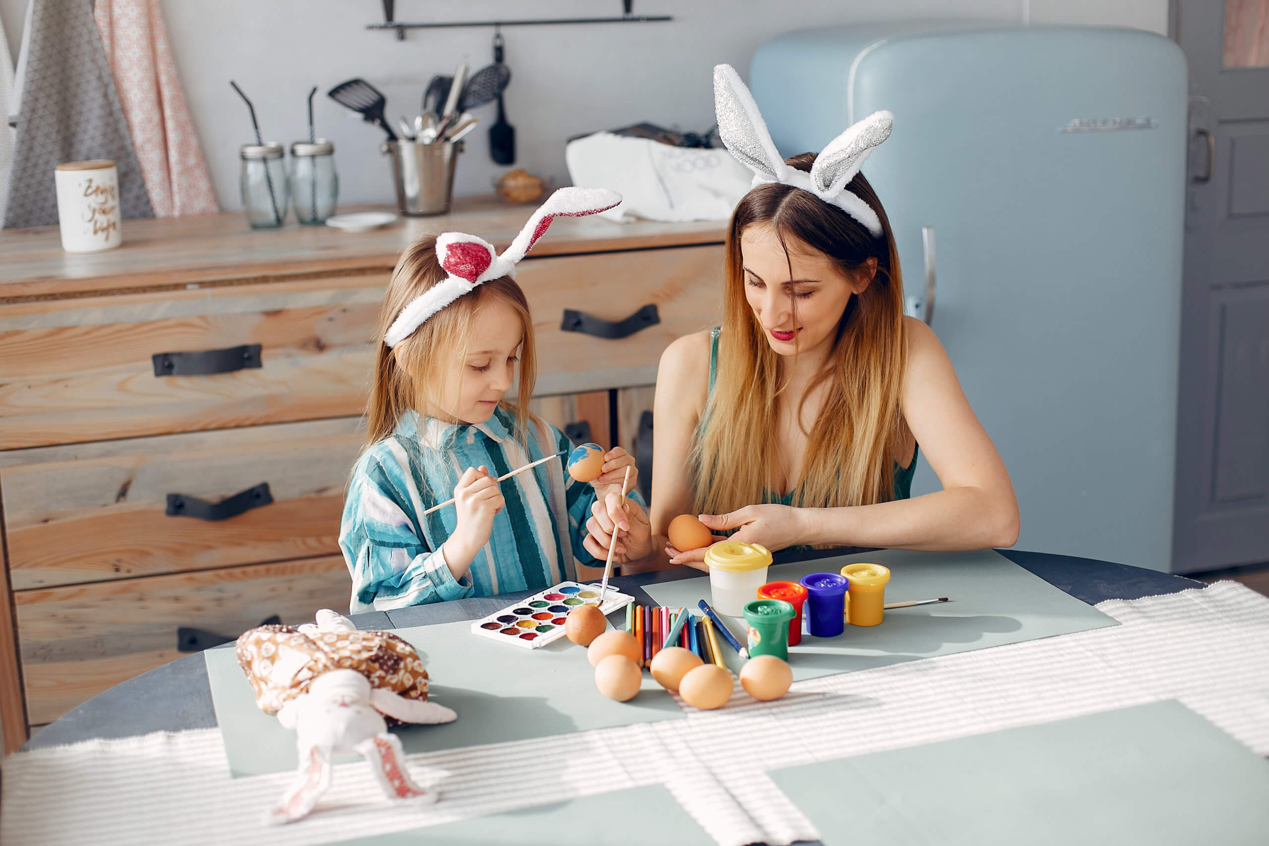 Mother and daughter paint eggs. Family in a kitchen. Preparing for Easter