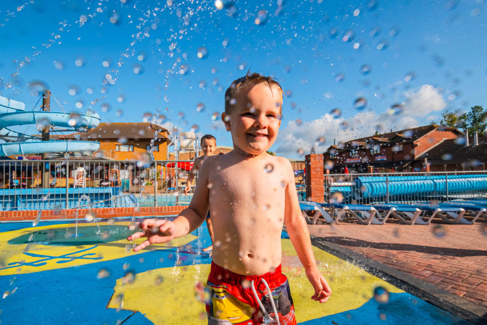 A young boy, smiling in a splash zone