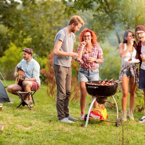 Holiday park BBQ safety - group enjoying safe BBQ near tent.