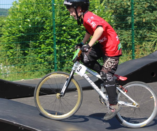 A young boy wearing safety gear riding his bike at the Lady's Mile pump track